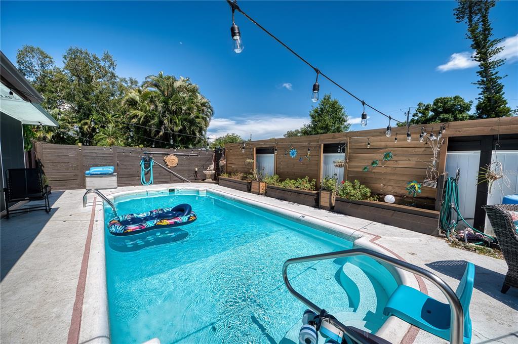 A backyard swimming pool features a concrete deck, string lights, and a wooden privacy fence — 4108 PRESCOTT STREET, SARASOTA, FL