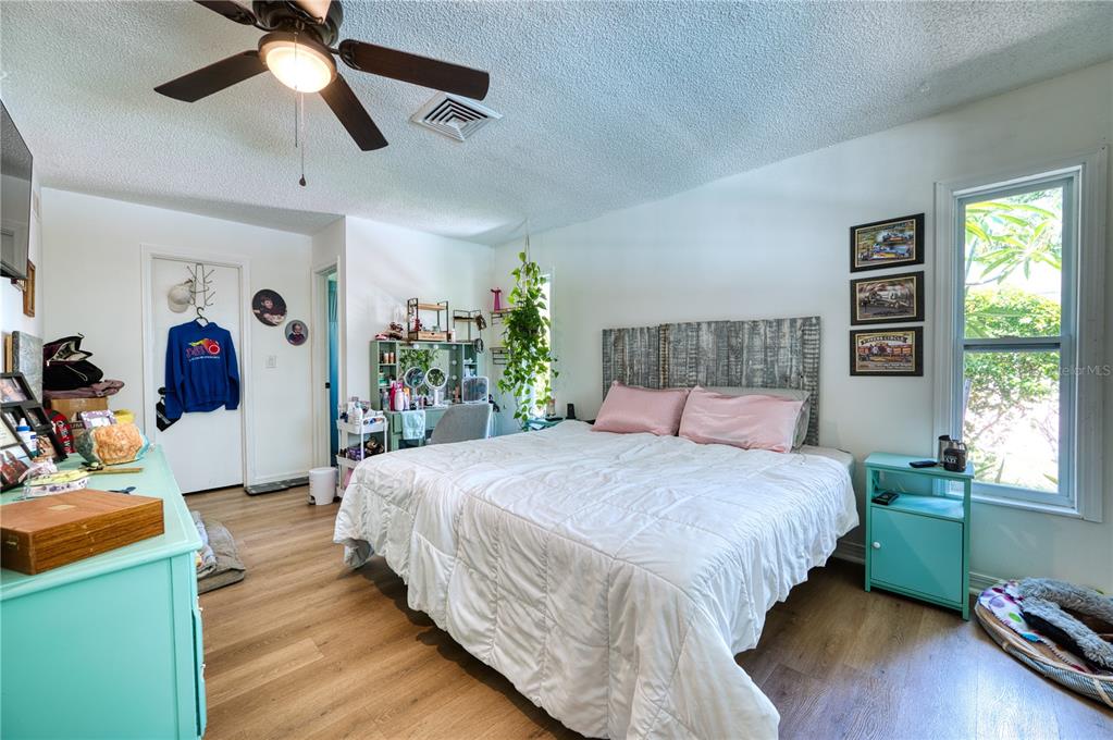 A bedroom features a bed with a wooden headboard, light wood flooring, and a ceiling fan — 4108 PRESCOTT STREET, SARASOTA, FL