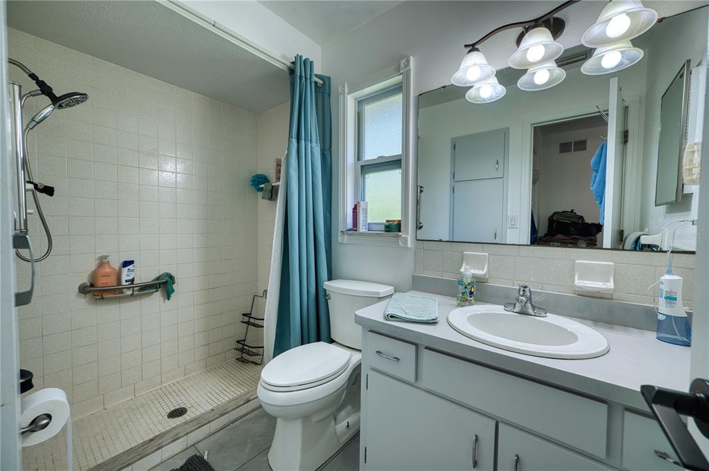 A bathroom features a tiled walk-in shower, a white toilet, and a gray vanity — 4108 PRESCOTT STREET, SARASOTA, FL