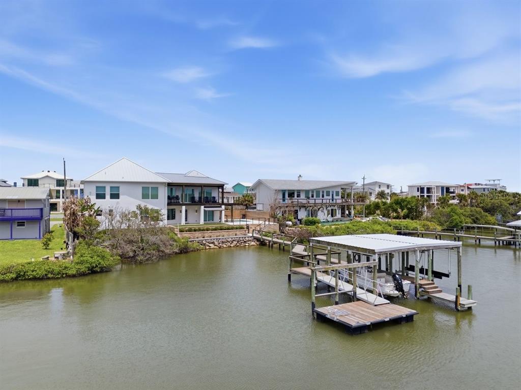 A waterfront house with a boat dock and lift sits along a canal — 7050 TURTLEMOUND ROAD, NEW SMYRNA BEACH, FL