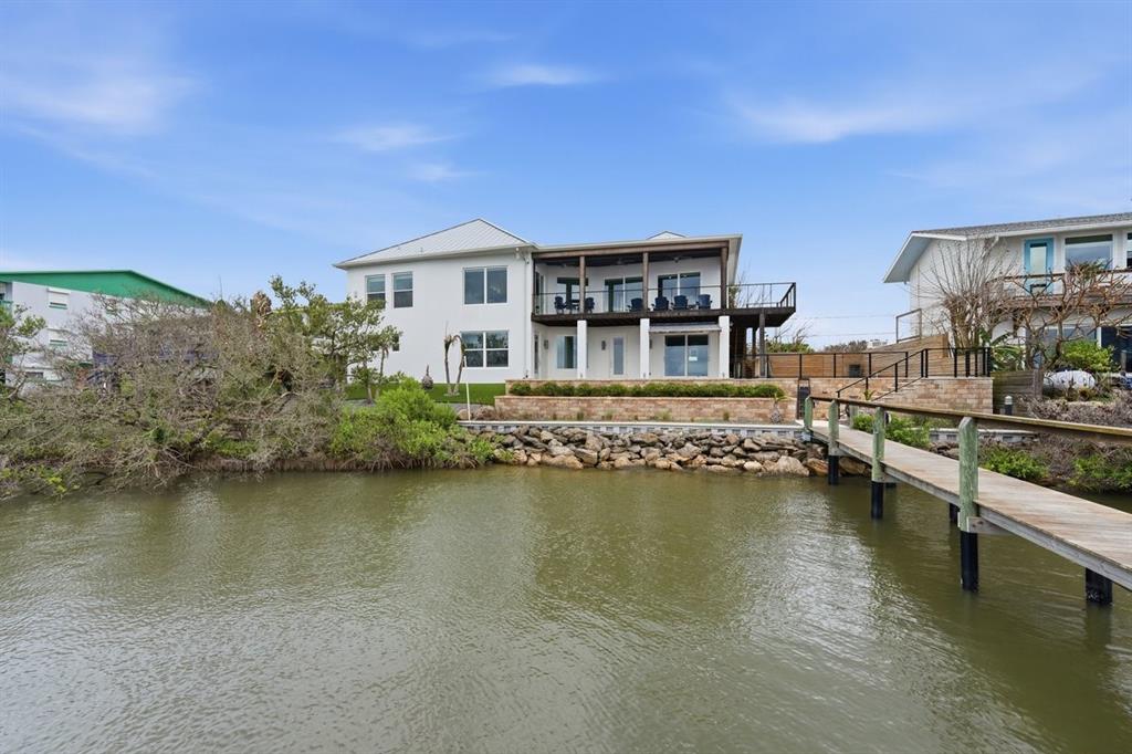 A white two-story house with a wooden deck and pier overlooking a body of water — 7050 TURTLEMOUND ROAD, NEW SMYRNA BEACH, FL