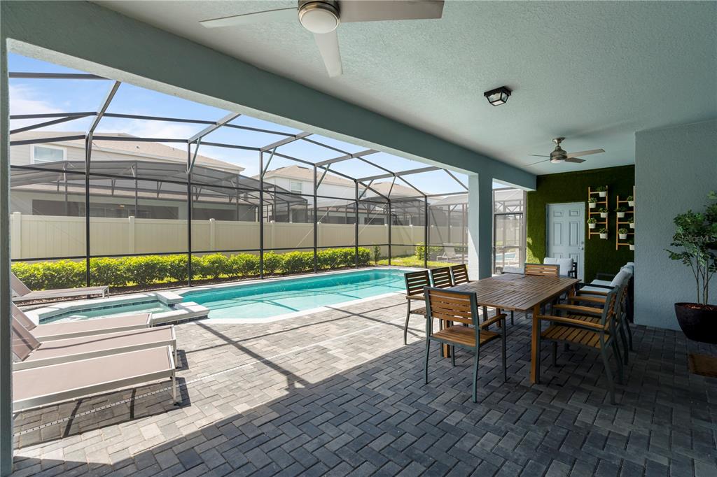 A covered patio features a dining set, lounge chairs, and a swimming pool with a screen enclosure — 3625 LILY LANE, DAVENPORT, FL