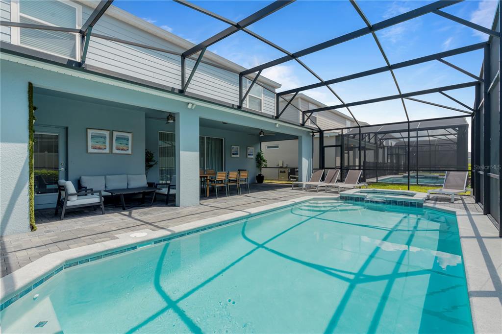 A screened-in patio features a swimming pool, a hot tub, and outdoor seating area — 3625 LILY LANE, DAVENPORT, FL