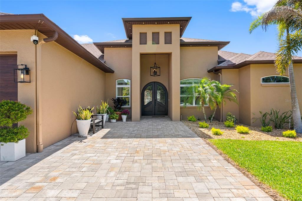 The exterior of a tan stucco house features a paved walkway leading to double doors — 17117 LAKESHORE ROAD, LUTZ, FL