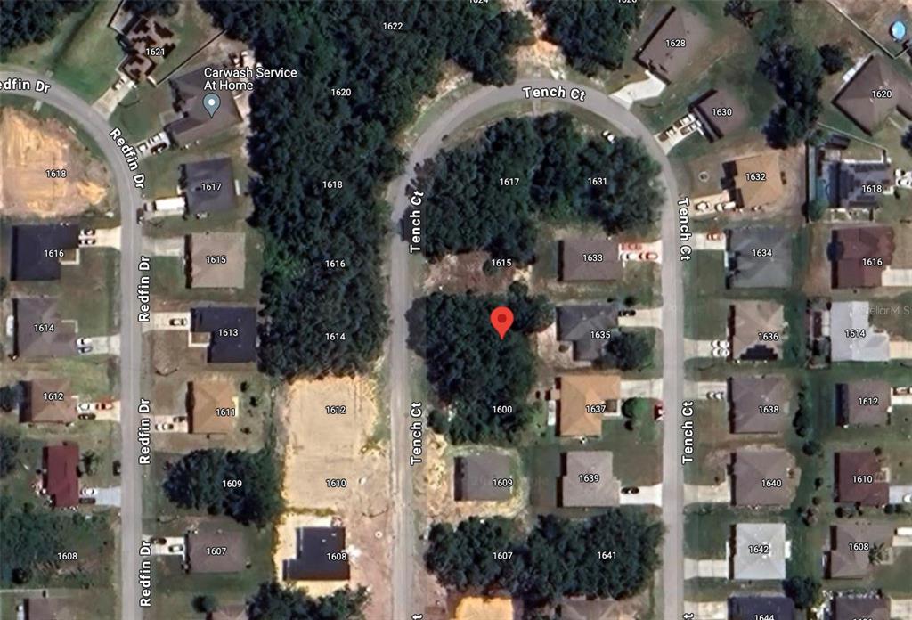 This is an aerial map view of a residential neighborhood with houses and wooded lots — 1613 TENCH COURT, POINCIANA, FL