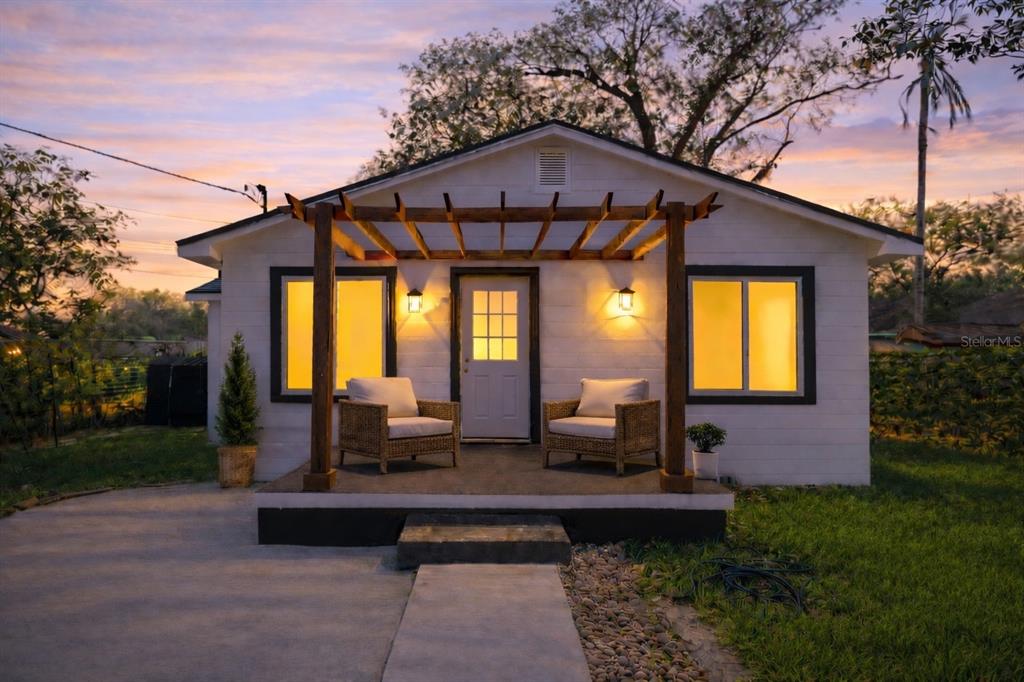 A small white house with a wooden pergola over the front porch and two chairs — 2102 E CARACAS STREET, TAMPA, FL
