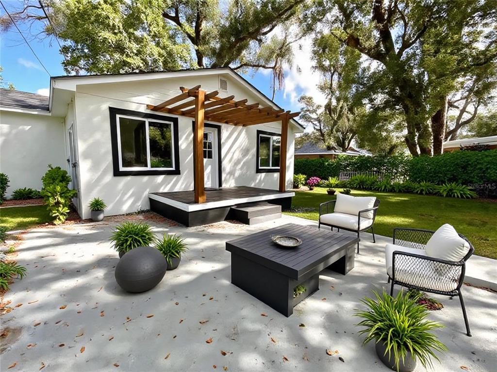 A white house with a wooden pergola over a deck and a concrete patio area — 2102 E CARACAS STREET, TAMPA, FL
