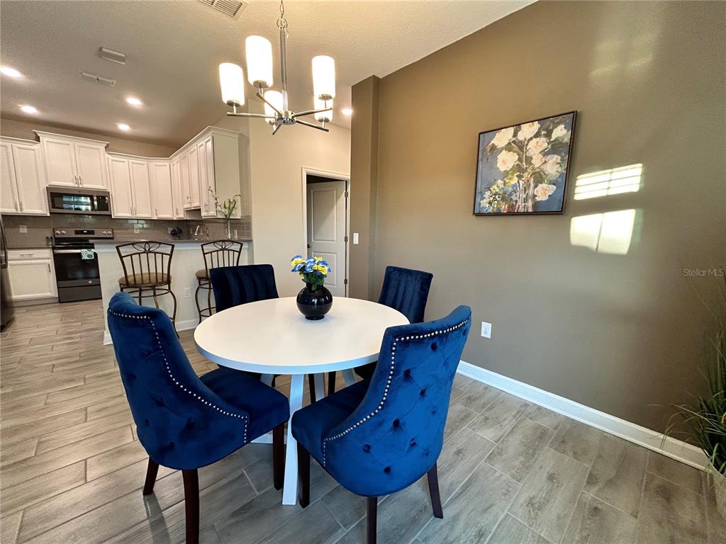 A dining area features a round white table, blue velvet chairs, and a chandelier — 1159 TRAPPERS TRAIL LOOP, DAVENPORT, FL