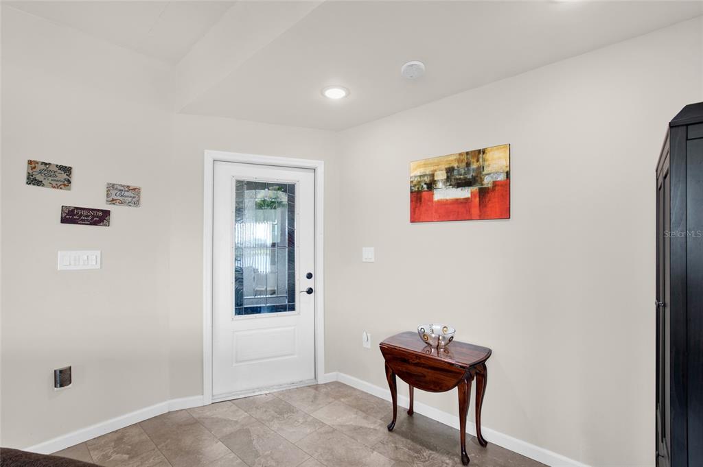 An entryway features a white front door with a glass insert, tile flooring, and wall art — 312 CLUB COVE DRIVE, TITUSVILLE, FL
