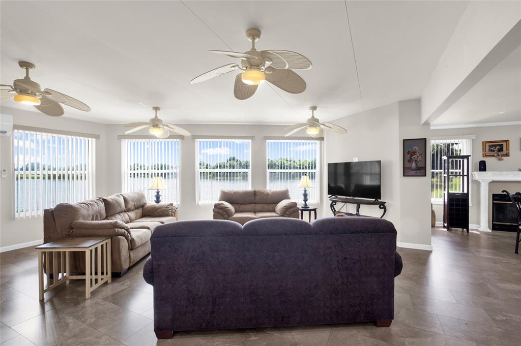 A living room features tile floors, three ceiling fans, and a view of the water — 312 CLUB COVE DRIVE, TITUSVILLE, FL