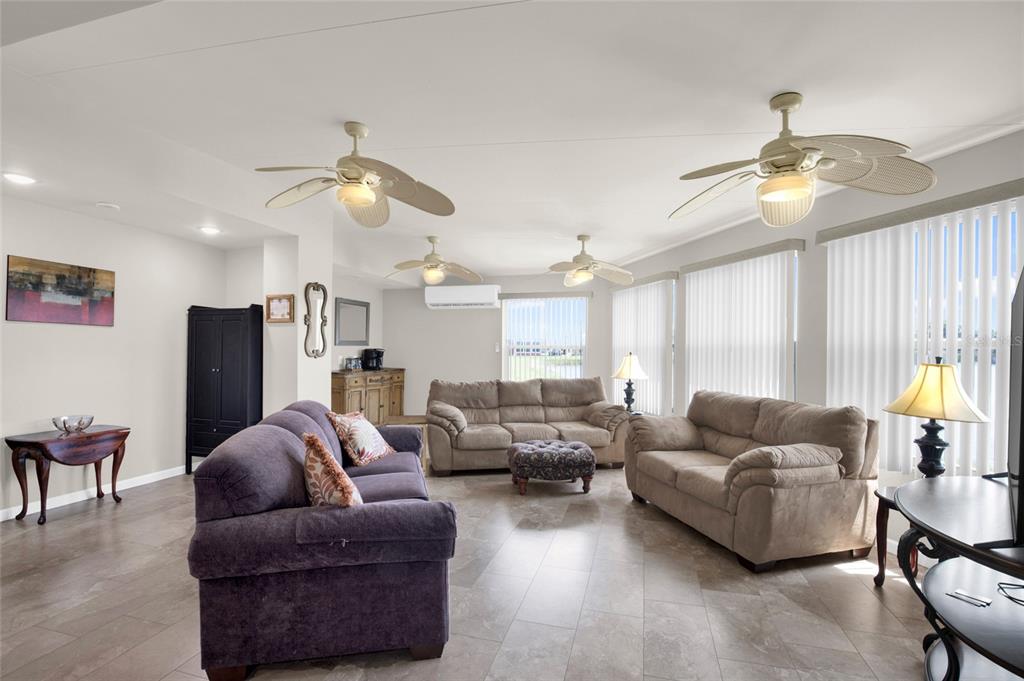 A living room features tile flooring, three ceiling fans, and three sofas arranged around an ottoman — 312 CLUB COVE DRIVE, TITUSVILLE, FL