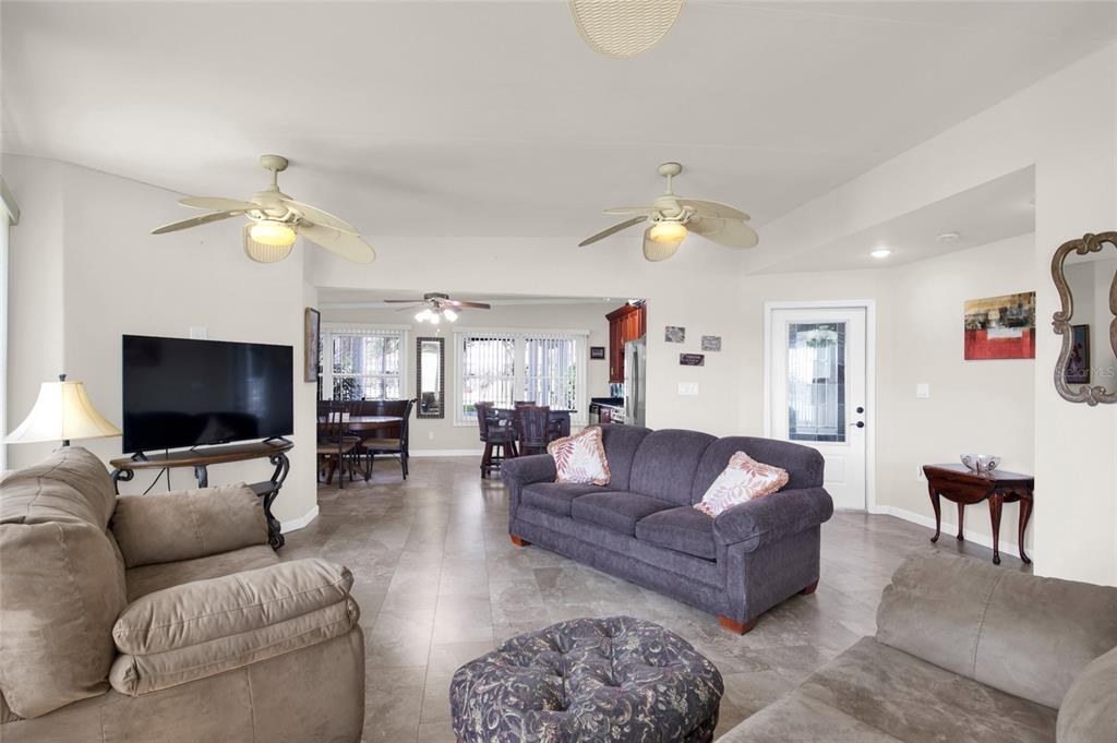 A living room with tile floors, two ceiling fans, and a dark grey sofa — 312 CLUB COVE DRIVE, TITUSVILLE, FL