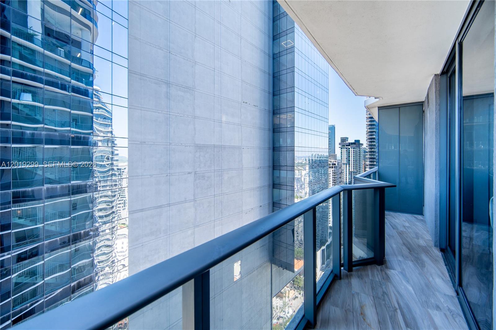 A modern balcony with glass railings overlooks a dense urban skyline of glass skyscrapers — 801 S Miami Ave # 3905, Miami FL 33130, MIAMI, FL