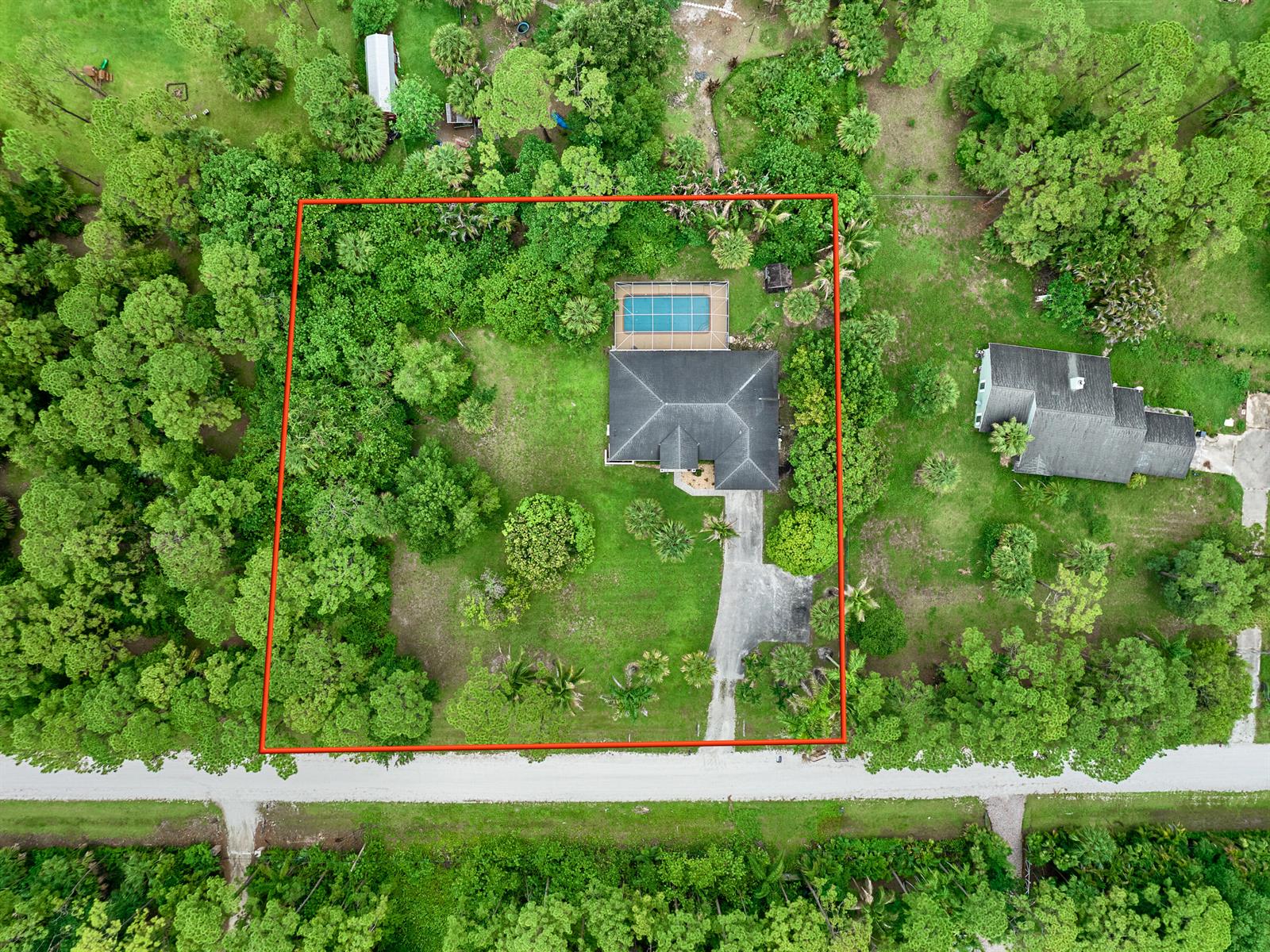 An aerial view shows a house with a pool and fenced yard surrounded by trees — 16405 90th Street N, FL 33470, FL