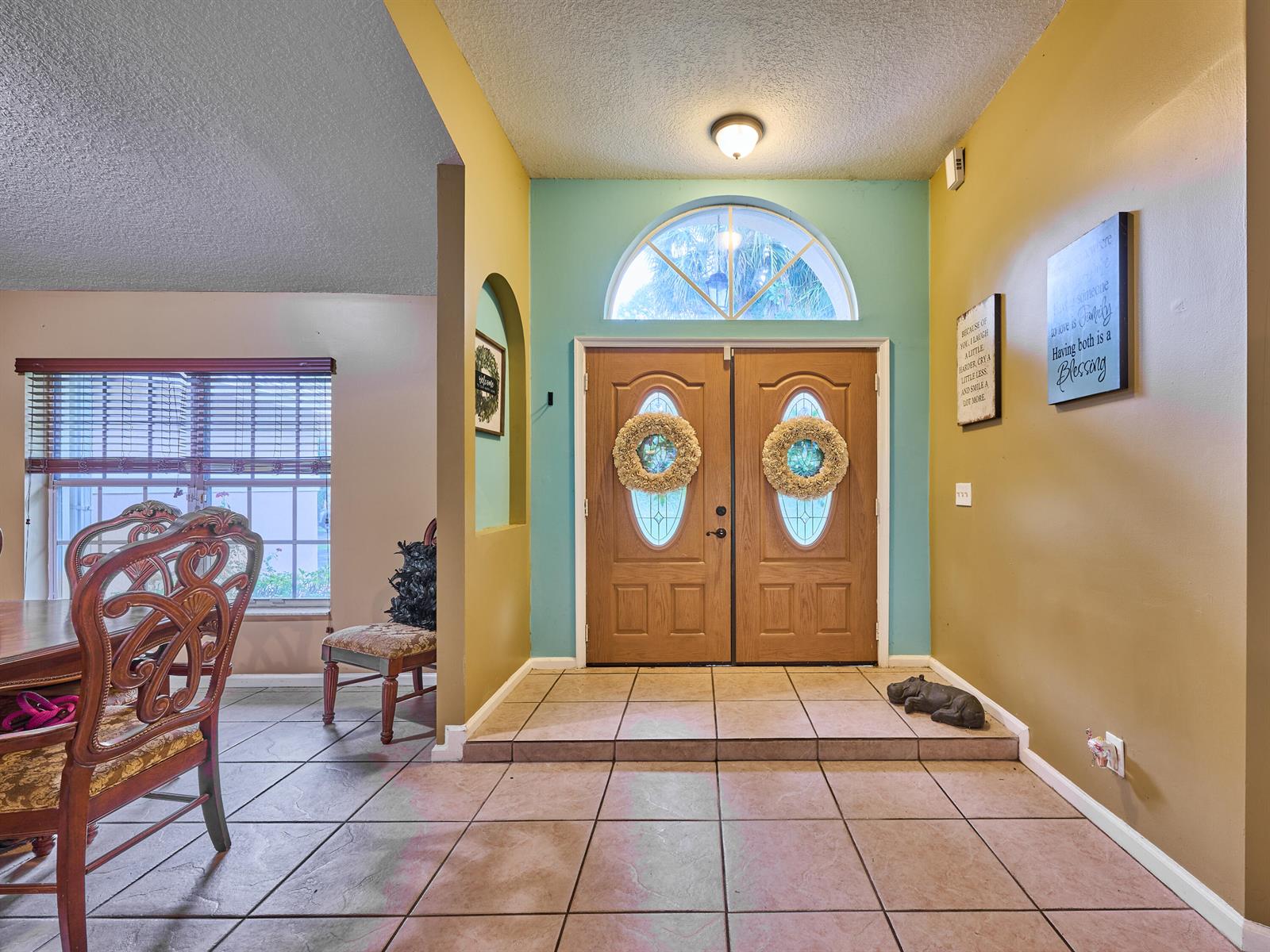 An entryway with tile flooring, double wood doors, and a teal accent wall — 16405 90th Street N, FL 33470, FL