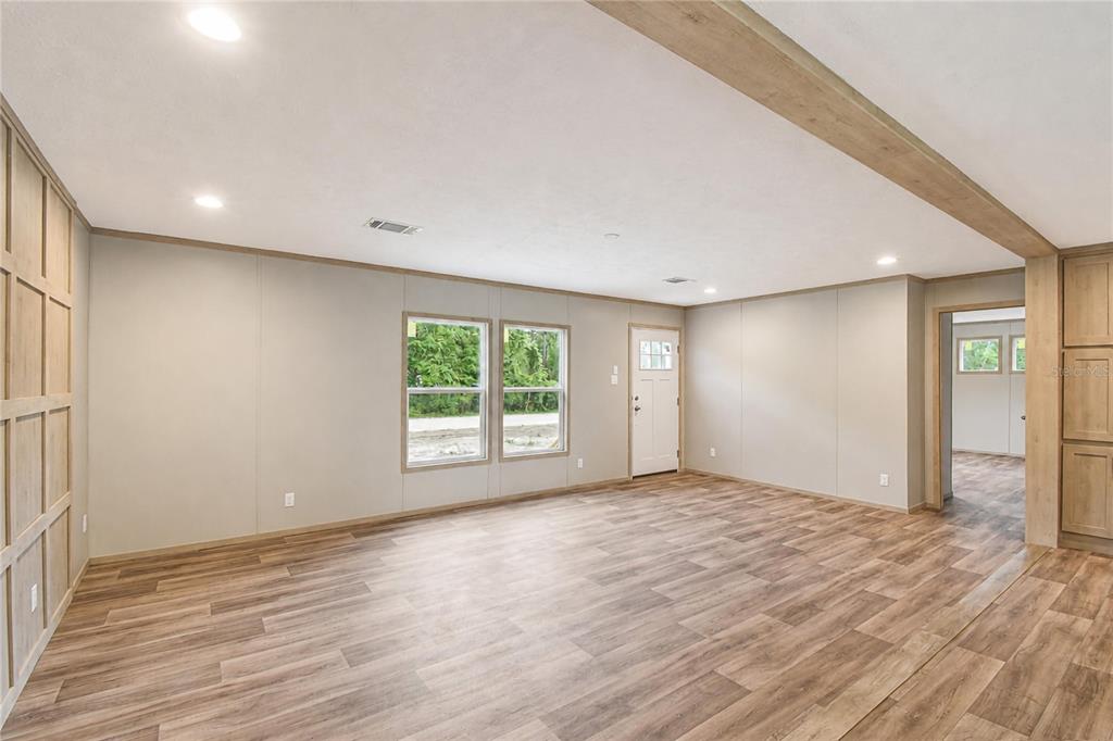 An interior view of a living room with wood-look flooring, paneled walls, and recessed lighting — 5235 SW 161ST CT ROAD, OCALA, FL