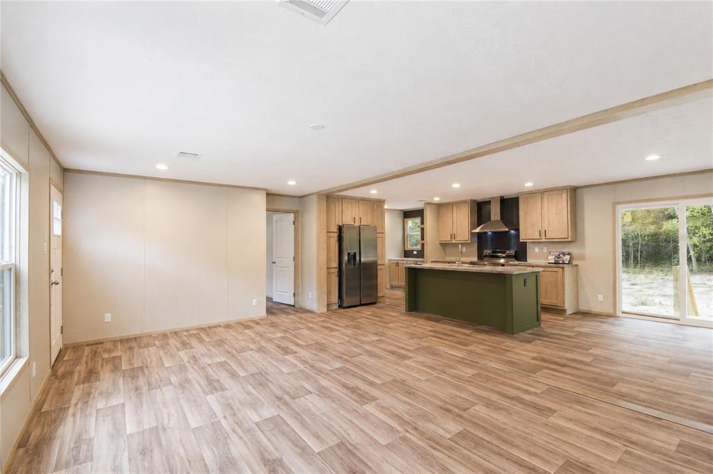 An open-concept kitchen and living area features light wood cabinets, a green island, and flooring — 5235 SW 161ST CT ROAD, OCALA, FL