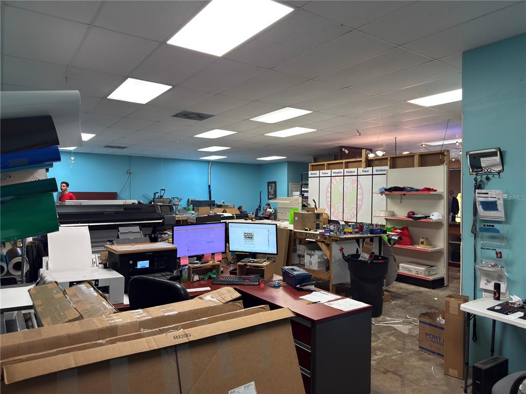 A commercial workspace features computer workstations, large-format printers, shelving units, and blue walls — 1109 TAMIAMI TRAIL UNIT 5, PORT CHARLOTTE, FL