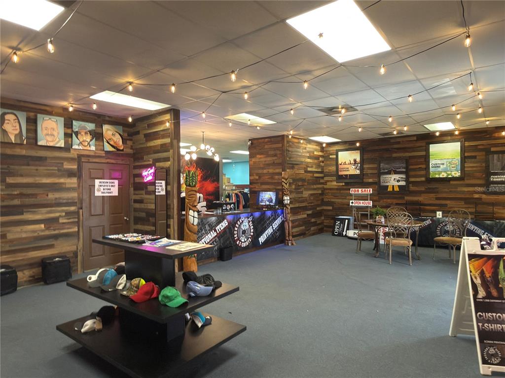 A retail space features wood-paneled walls, a central display stand for hats, and string lighting — 1109 TAMIAMI TRAIL UNIT 5, PORT CHARLOTTE, FL