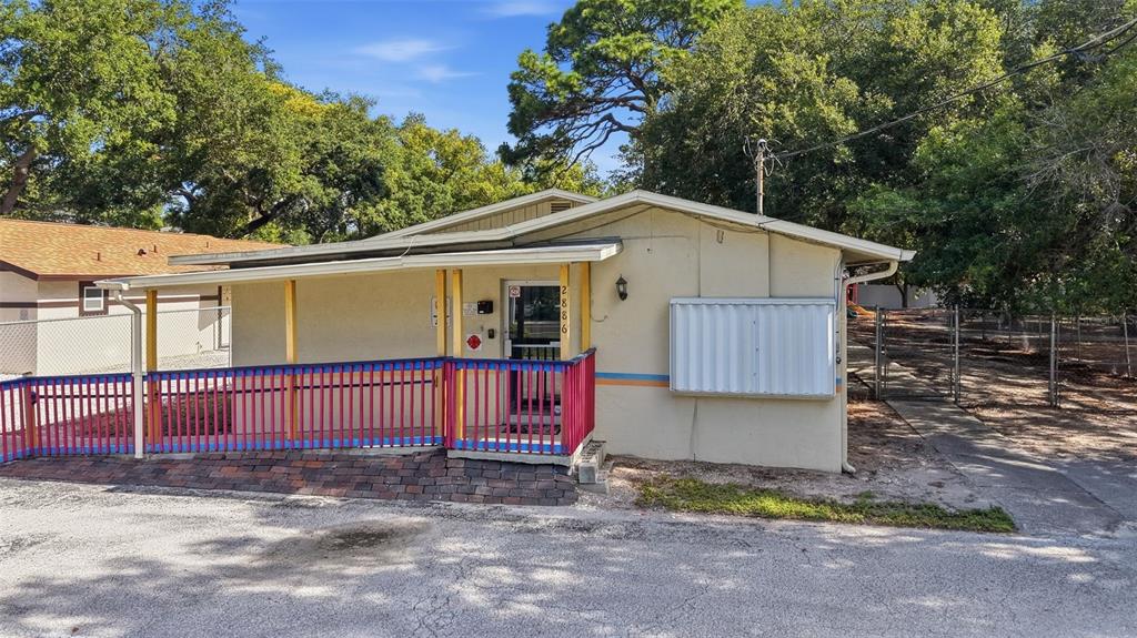 A single-story building features a covered porch with a red and blue railing — 2886 WHITNEY ROAD, CLEARWATER, FL