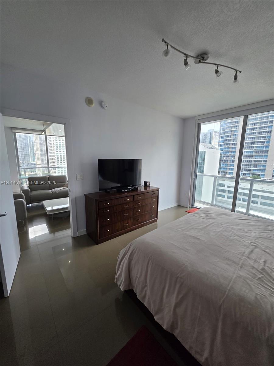 A bedroom features a bed, a wooden dresser with a television, and a balcony view — 1060 Brickell Ave # 2201, Miami FL 33131, MIAMI, FL