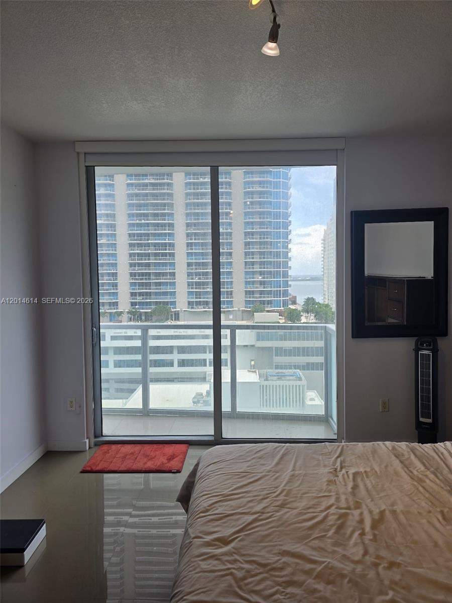 A bedroom features a large sliding glass door overlooking a balcony and high-rise buildings — 1060 Brickell Ave # 2201, Miami FL 33131, MIAMI, FL