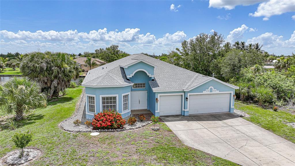 An aerial view of a light blue single-story house with a two-car garage and lawn — 9436 PRESIDENT CIRCLE, PORT CHARLOTTE, FL