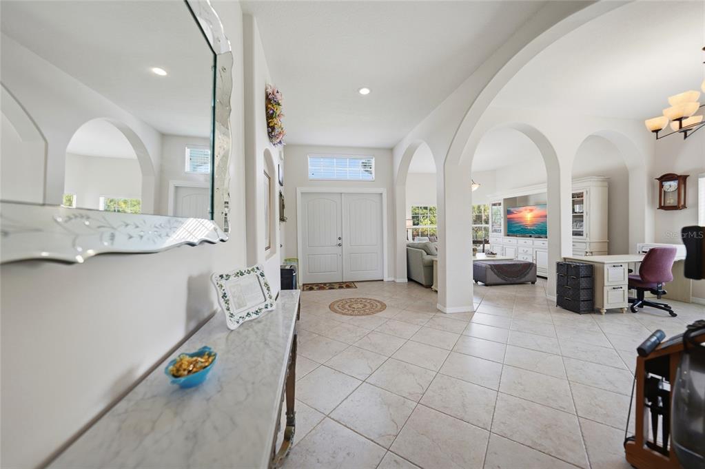 An entryway with tile floors leads to an open living area featuring multiple arched columns — 9436 PRESIDENT CIRCLE, PORT CHARLOTTE, FL