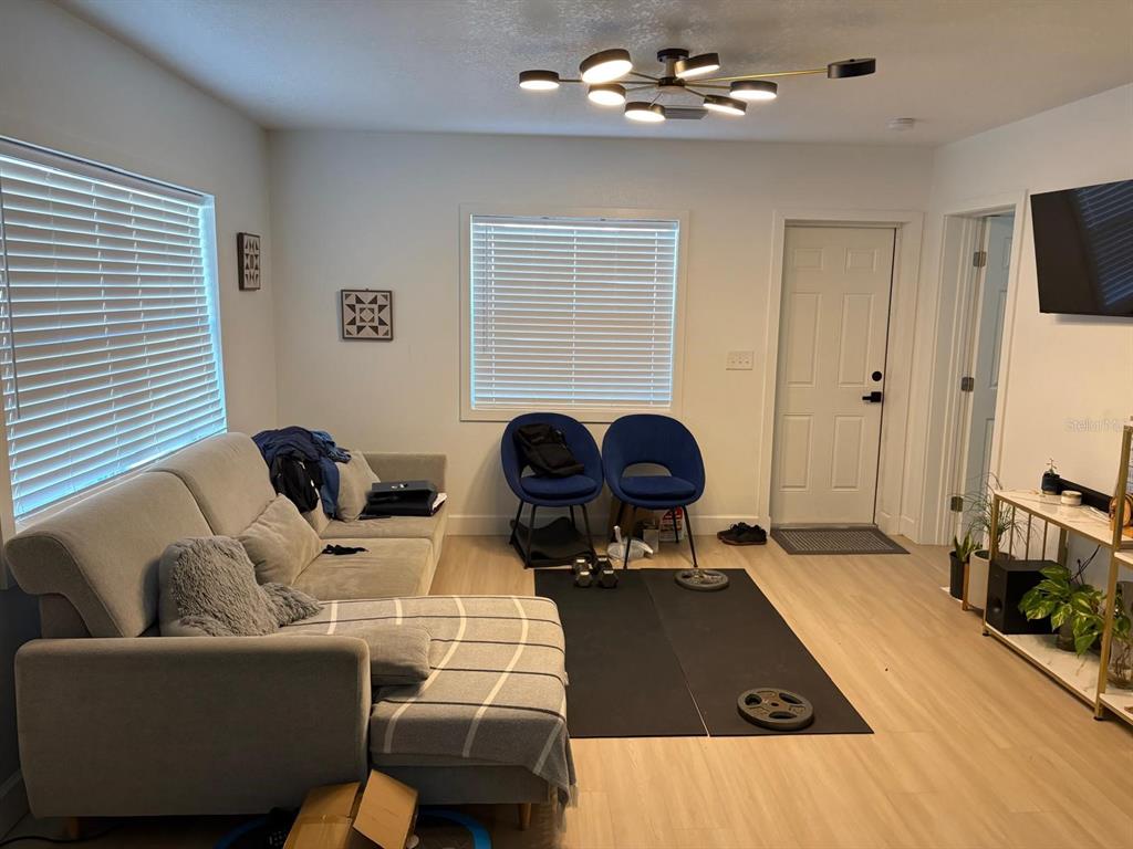 A living room features a grey sectional sofa, two blue chairs, and a workout mat — 215 ILLINOIS AVENUE, ST CLOUD, FL