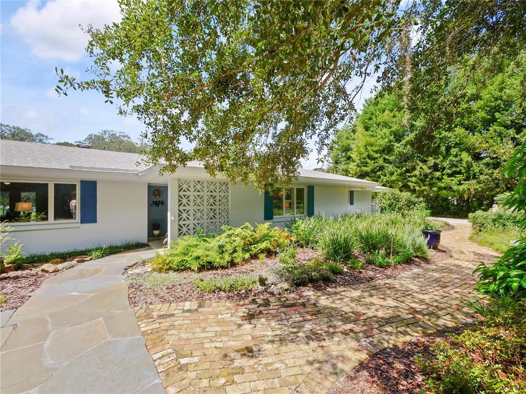 A white mid-century modern house features a decorative breeze block screen and brick walkway — 5701 CROSS FOX LANE, OVIEDO, FL