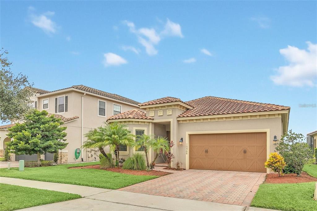 A single-story house with a tile roof, tan stucco exterior, and a two-car garage — 10466 STAPELEY DRIVE, ORLANDO, FL