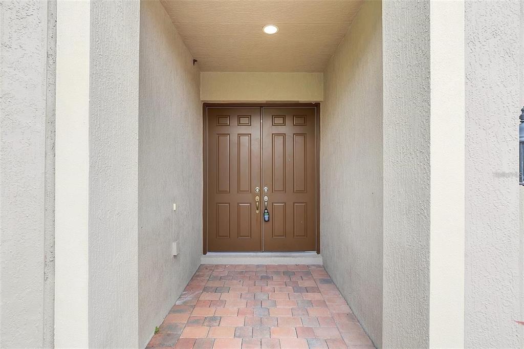 A recessed entryway features double brown doors and a paved brick floor — 10466 STAPELEY DRIVE, ORLANDO, FL