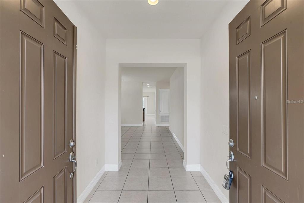 A view through an open doorway into a tiled entryway leading to a hallway — 10466 STAPELEY DRIVE, ORLANDO, FL