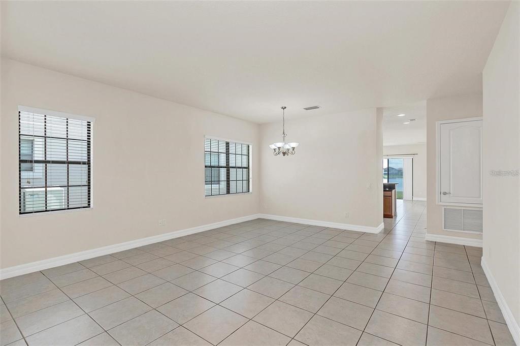 An empty dining area with light tile flooring, two windows, and a hanging light fixture — 10466 STAPELEY DRIVE, ORLANDO, FL