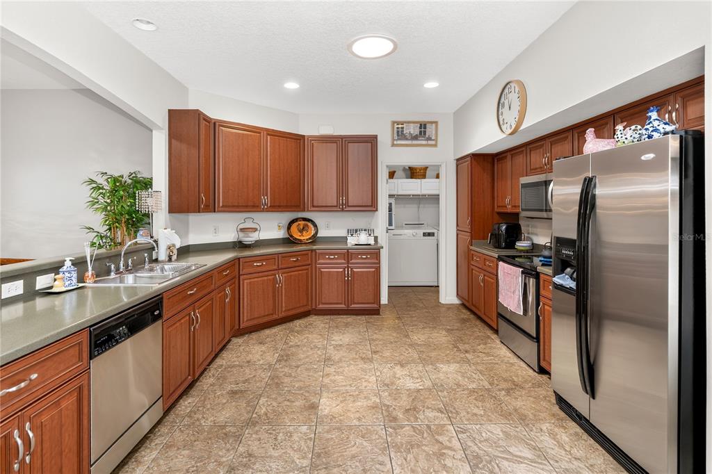 A kitchen features wood cabinets, stainless steel appliances, and tile flooring — 3393 BALTIC SEA BOULEVARD, TAVARES, FL