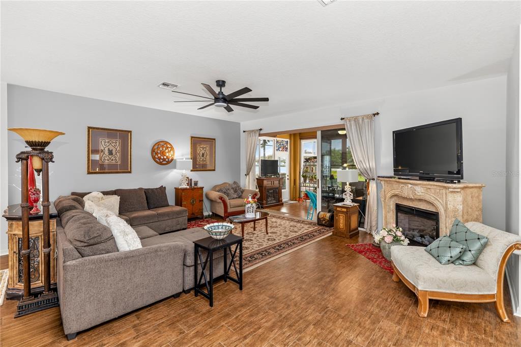 A living room features a sectional sofa, fireplace, and sliding glass doors leading to a lanai — 3393 BALTIC SEA BOULEVARD, TAVARES, FL