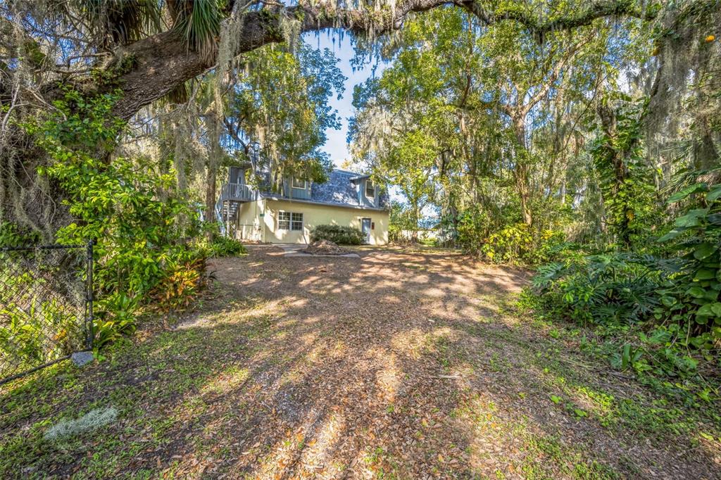 A two-story yellow house sits at the end of a dirt driveway under large trees — 9401 CAT TRACK TRAIL, LAKE WALES, FL