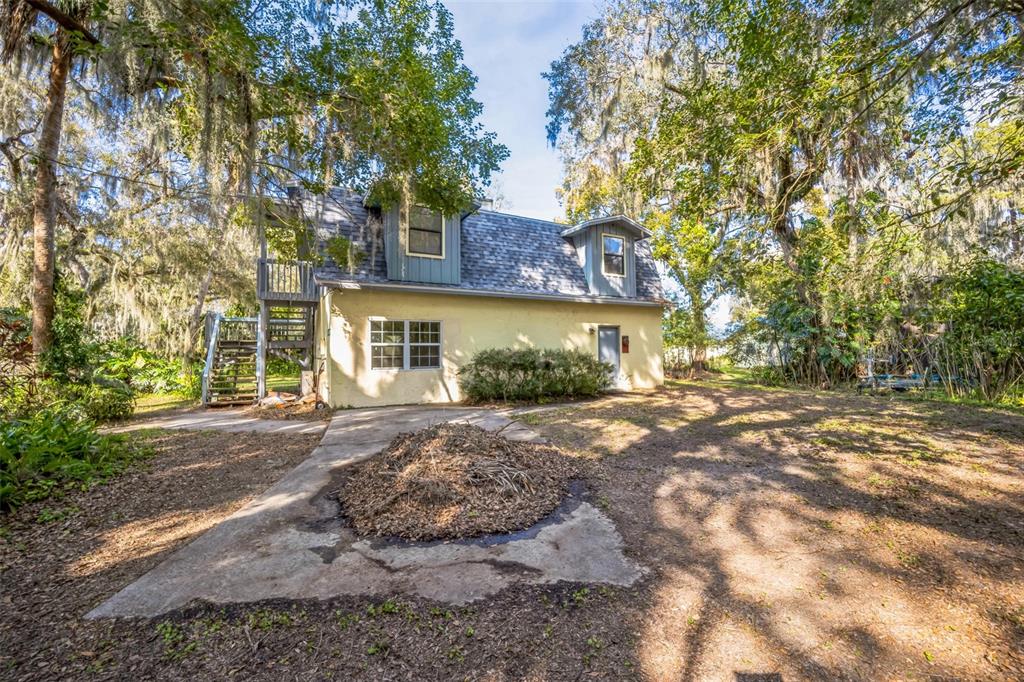 A two-story house with a yellow exterior, a gray roof, and an outdoor wooden staircase — 9401 CAT TRACK TRAIL, LAKE WALES, FL