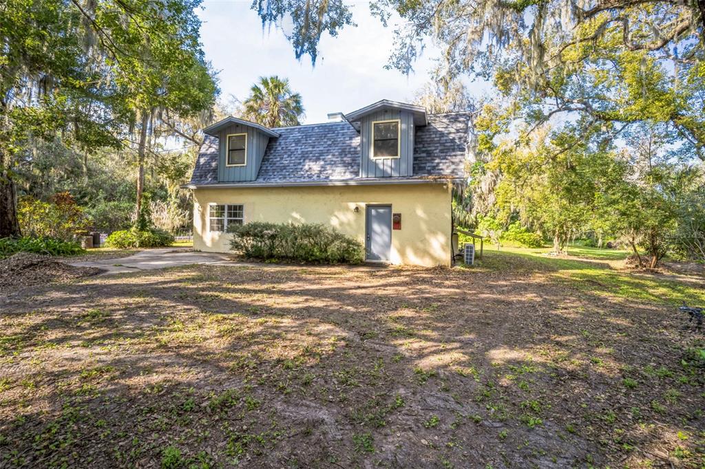 A two-story house with a yellow stucco exterior and two dormer windows sits in a yard — 9401 CAT TRACK TRAIL, LAKE WALES, FL