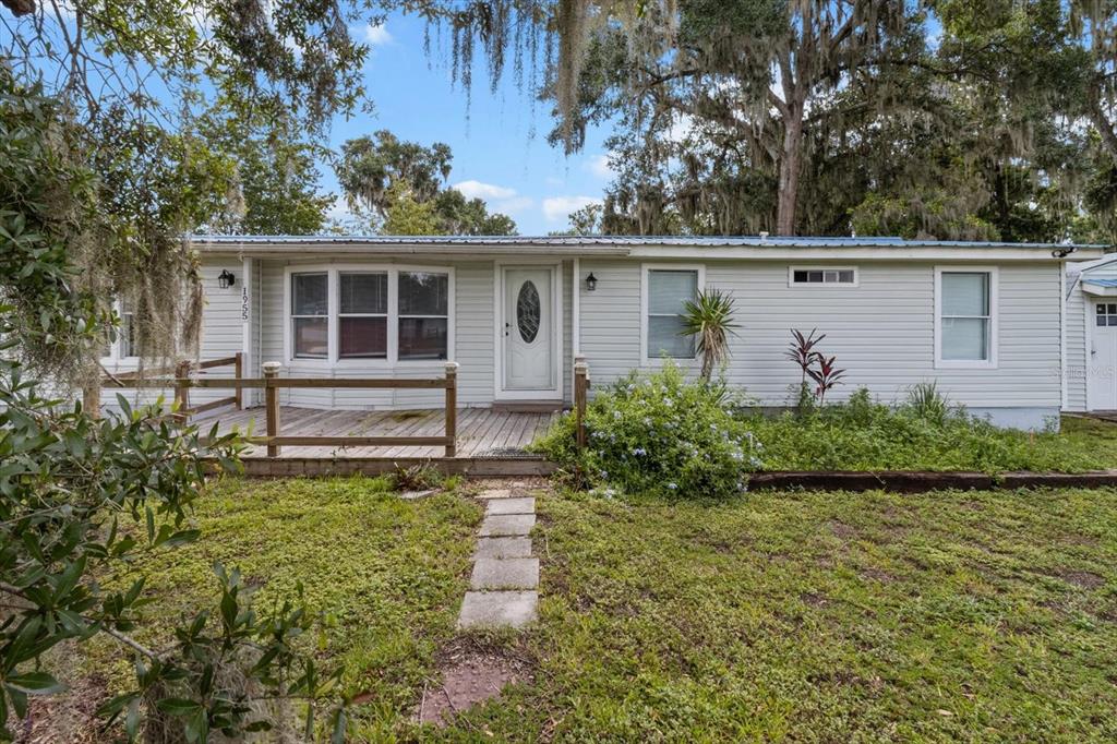 A single-story house with light gray siding, a wooden front deck, and a stone walkway — 1955 CR 439C, LAKE PANASOFFKEE, FL