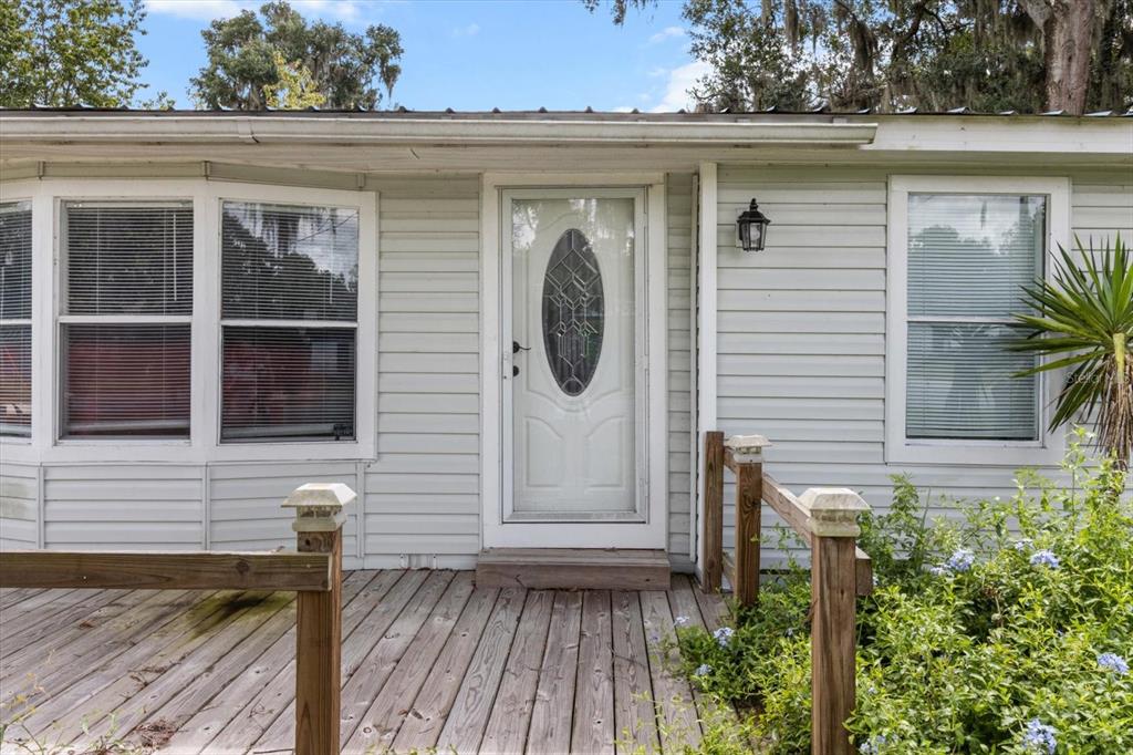 A white house exterior features a wooden deck, a front door, and two windows — 1955 CR 439C, LAKE PANASOFFKEE, FL