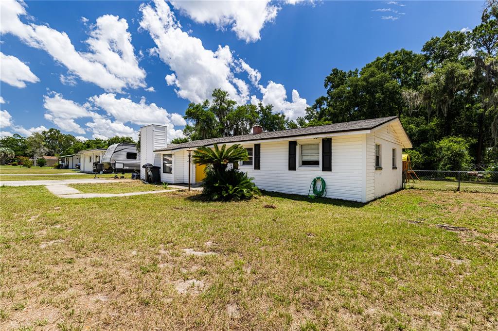 A white, single-story house with black shutters sits on a grassy lot under a cloudy sky — 294 SE TRIBBLE STREET, LAKE CITY, FL