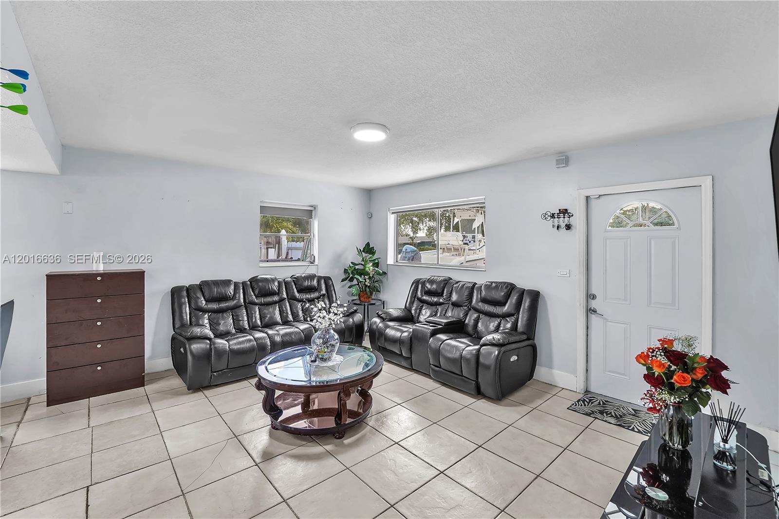 A living room features light-colored tile flooring, two black leather sofas, and a glass coffee table — 900 N 70th Ave, Hollywood FL 33024, HOLLYWOOD, FL