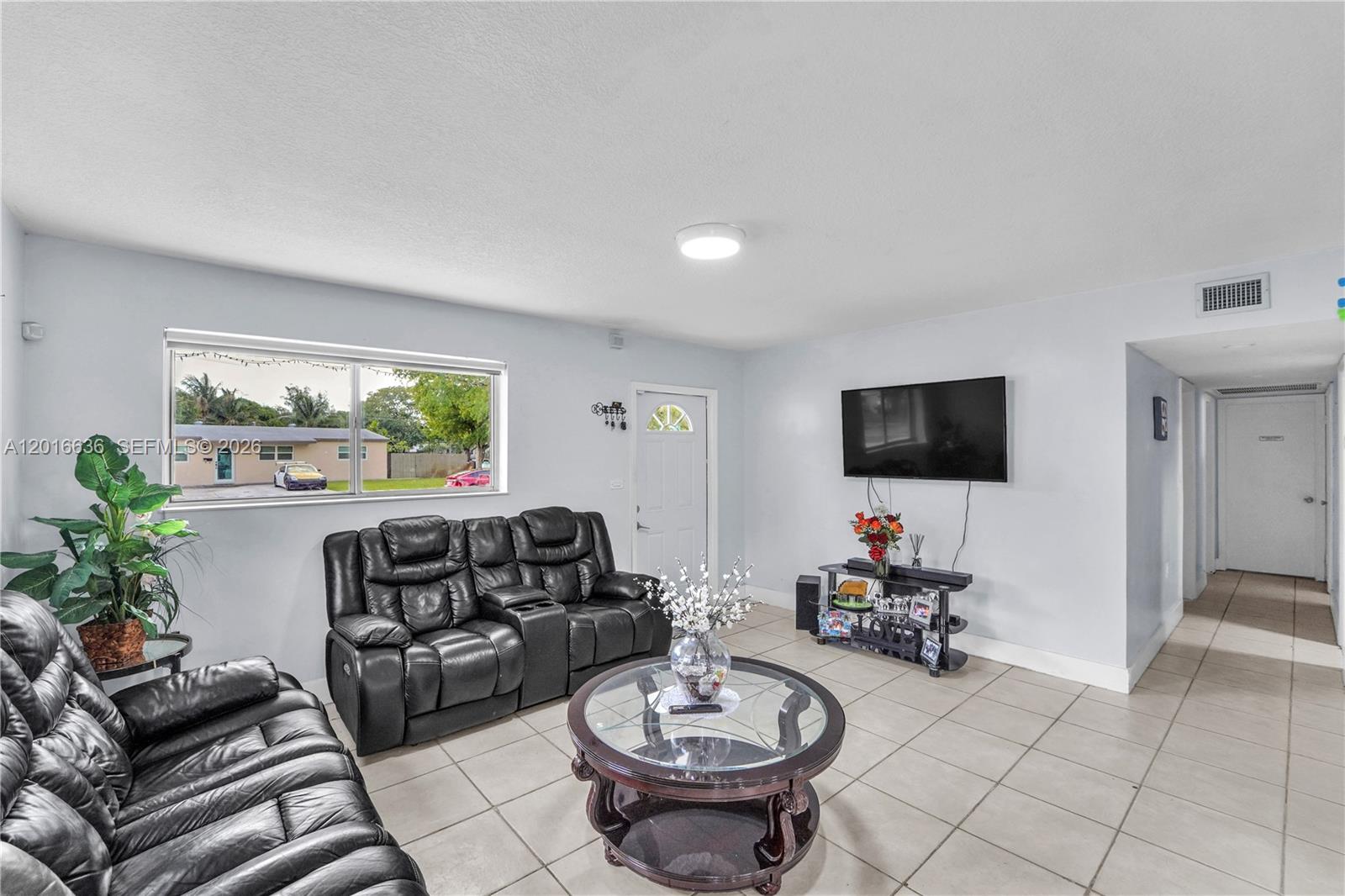 A living room features black leather sofas, a glass coffee table, and tile flooring — 900 N 70th Ave, Hollywood FL 33024, HOLLYWOOD, FL