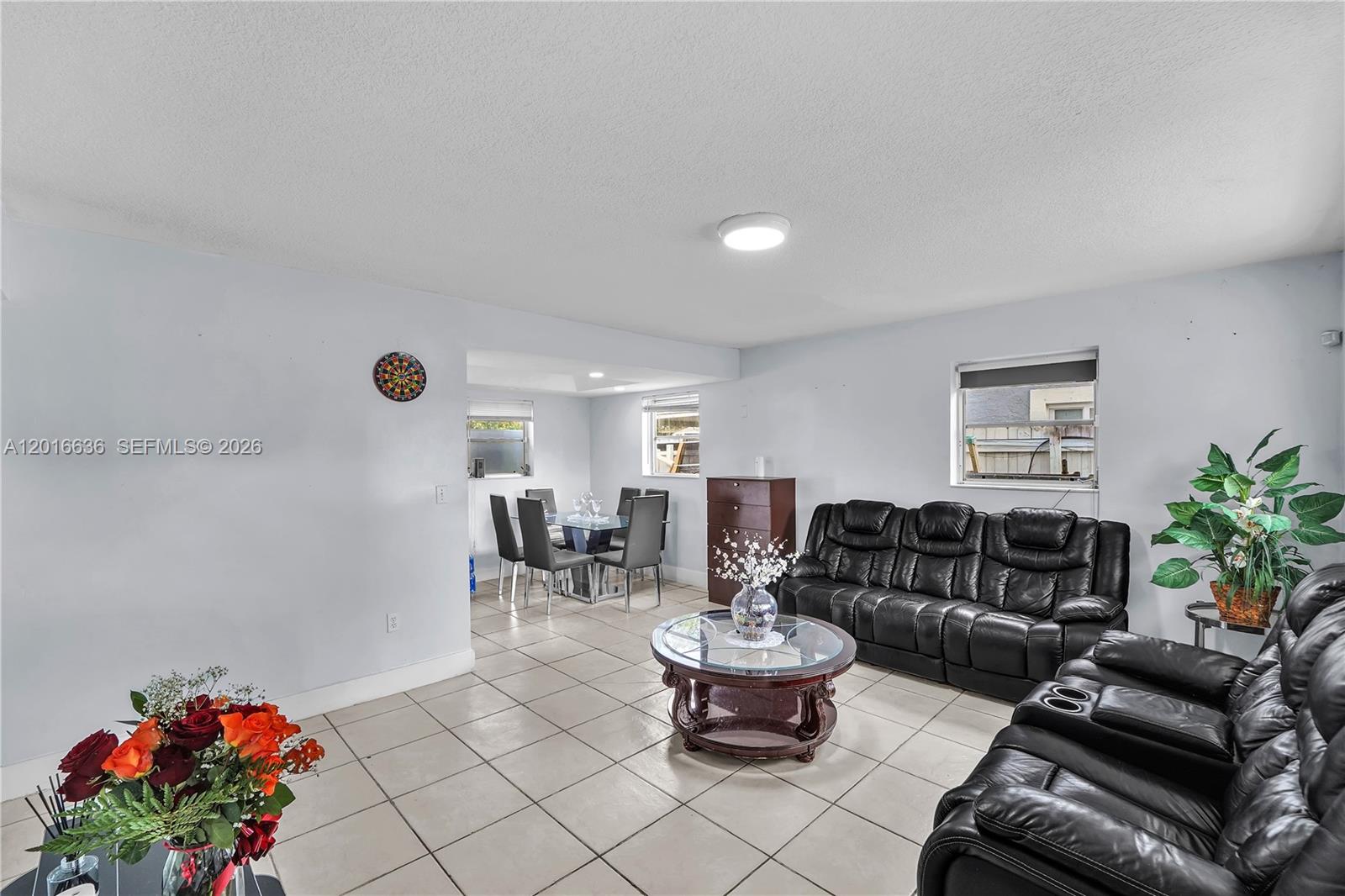 A living room and dining area feature light-colored tile flooring and black leather furniture — 900 N 70th Ave, Hollywood FL 33024, HOLLYWOOD, FL