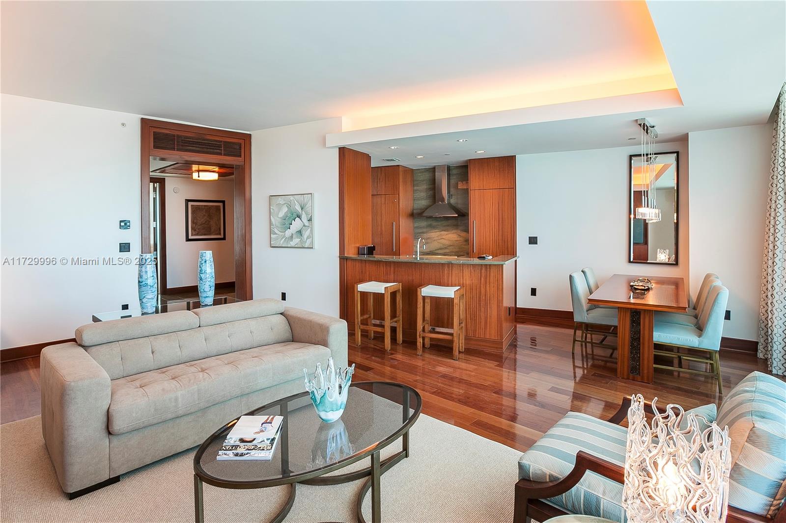 A living room with a sofa, coffee table, kitchen island, and dining area with wood floors — 10295 Collins Ave, Bal Harbour FL 33154, BAL HARBOUR, FL