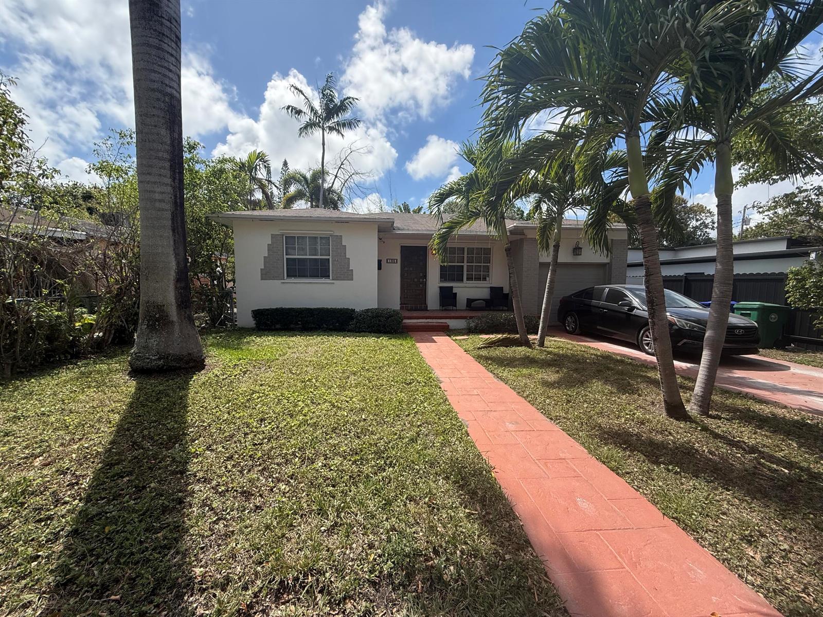 A single-story house with a red walkway, palm trees, and a black car parked outside — 130 NE 49th Street, Miami FL 33137, MIAMI, FL