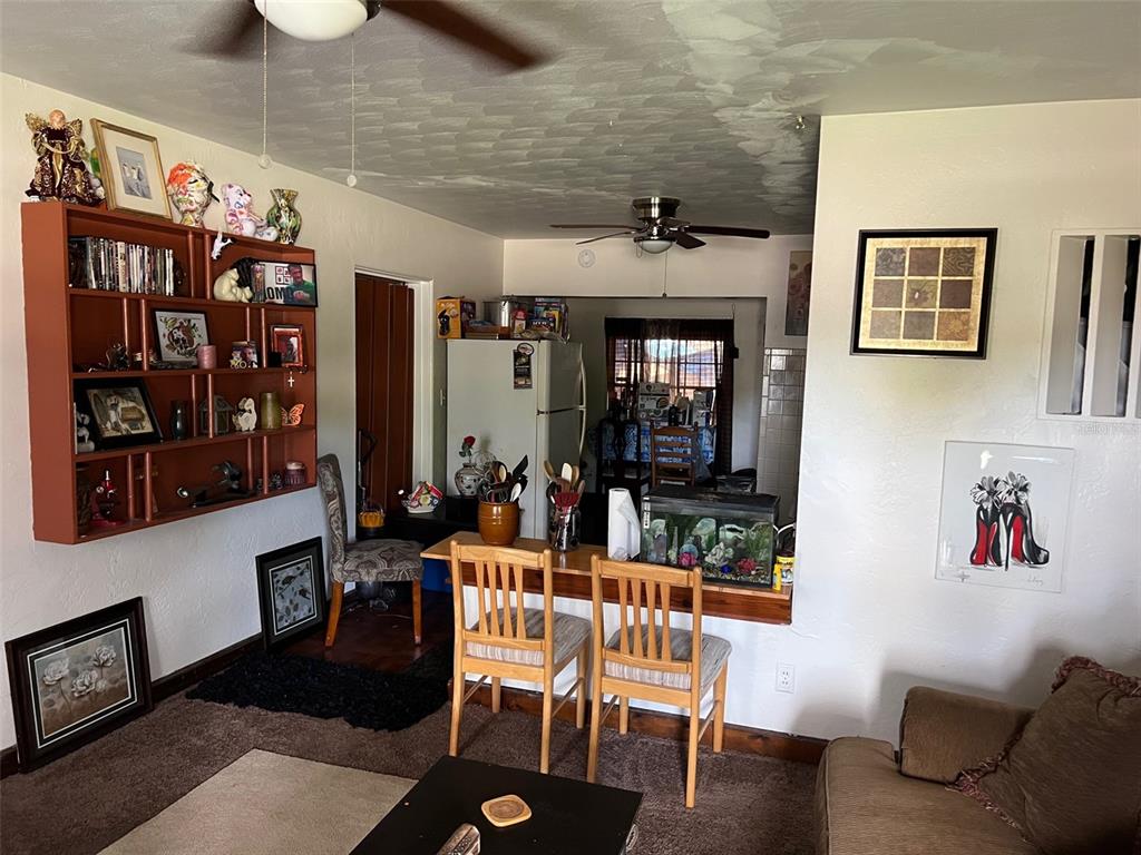 A living room features a wooden wall shelf, a breakfast bar with two chairs, and carpeting — 5634 5TH AVENUE N, ST PETERSBURG, FL