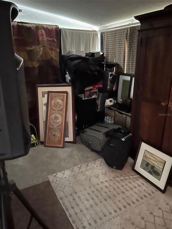 A cluttered room features a large wooden wardrobe, framed artwork, and various bags on carpet — 5634 5TH AVENUE N, ST PETERSBURG, FL