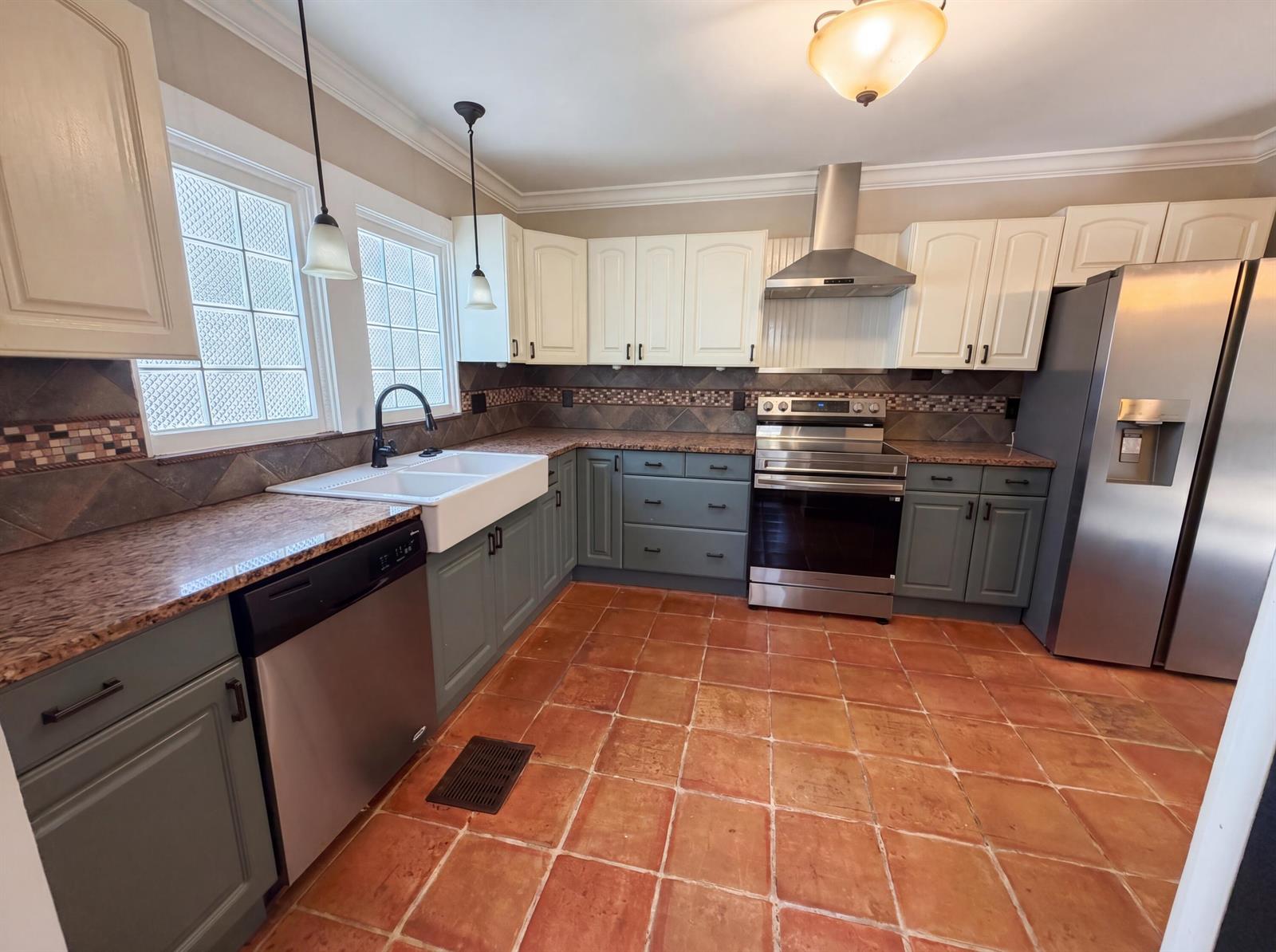 A kitchen features two-tone cabinets, granite countertops, stainless steel appliances, and terracotta floor tiles — 207 S Ocean Breeze, FL 33460, FL